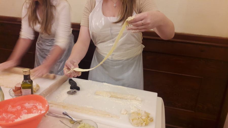 Le mani sollevano la sfoglia tirata a mano durante il corso di pasta fresca