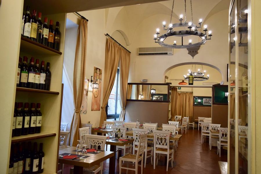 Dettaglio della sala: bottiglie di vino e stampe alle pareti