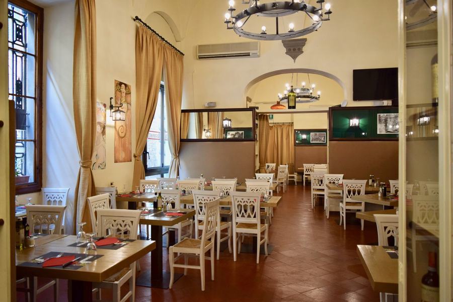 Una delle quattro sale comunicanti del ristorante, con pareti chiare e arredi in legno
